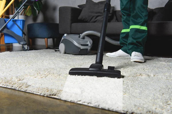 man cleaning a rug with a vacuum