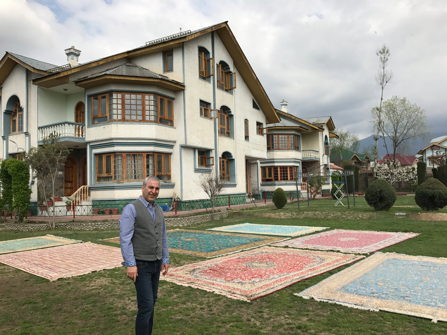 Owner showing rugs outside a house